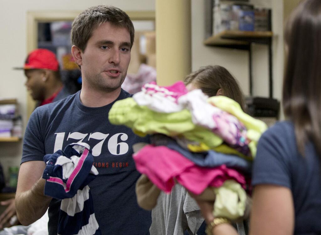 This, Dec. 16, 2014, photo shows Patrick McAnaney, from the company 1776, as he volunteers in the clothing room with a group of his coworkers at Bread for the City in Washington. Tired of hearing people grouse about a tuned-out, apathetic younger generation? Well, heres a comeback: Todays young Americans are serious when it comes to volunteering. In fact, measured against their parents as young adults back in the 1980s, those under 30 today are more likely to say that citizens have a very important obligation to give their time, an Associated Press-GfK poll finds. (AP Photo/Carolyn Kaster)