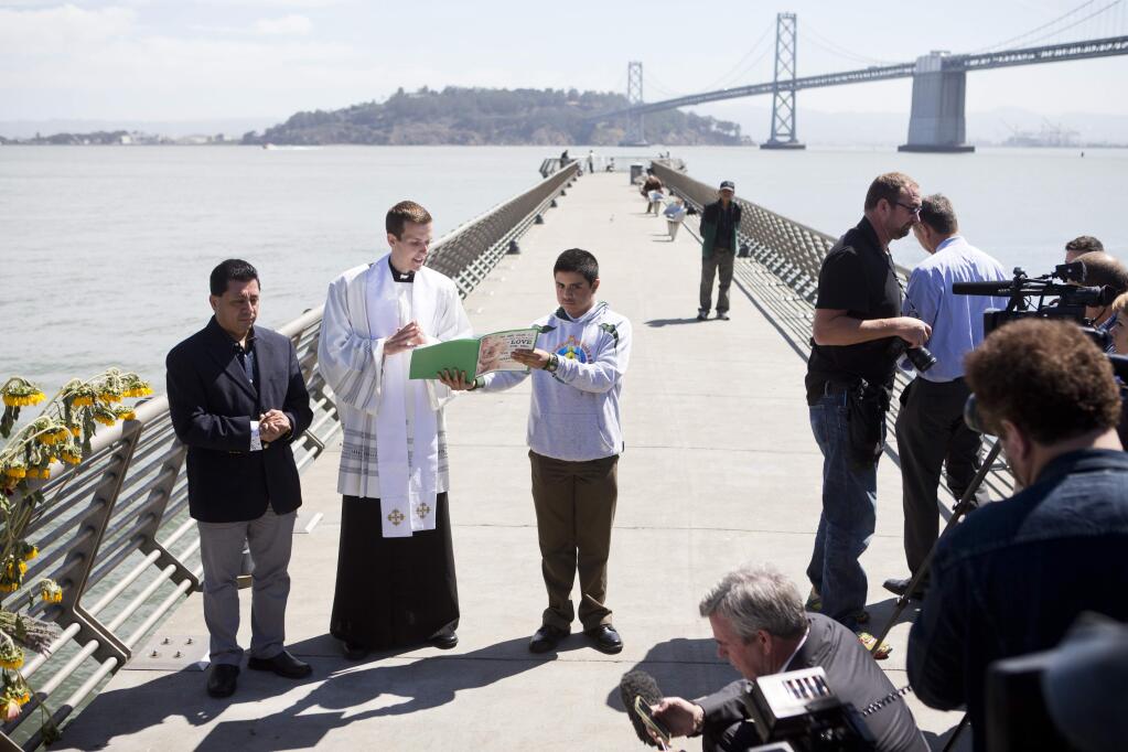 Father Cameron Faller, second left, of Restorative Justice Ministry conducts a vigil for Kathryn Steinle, Monday, July 6, 2015, on Pier 14 in San Francisco. Steinle was gunned down while out for an evening stroll at Pier 14 with her father and a family friend on Wednesday, July 1. (AP Photo/Beck Diefenbach)