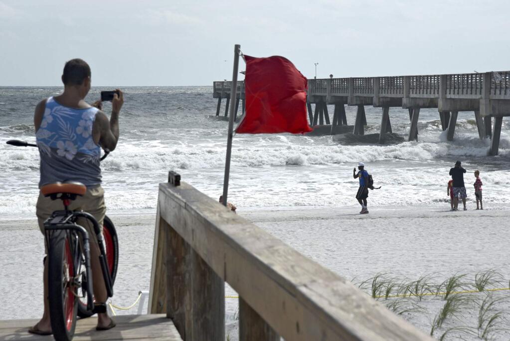 Christian Griffith films the high hazard flag flapping in the wind near the Jacksonville Beach Fishing Pier as the surf continues to build in advance of Hurricane, Irma, Friday Sept. 8, 2017, in Jacksonville Beach, Fla. (Bob Mack/The Florida Times-Union via AP)