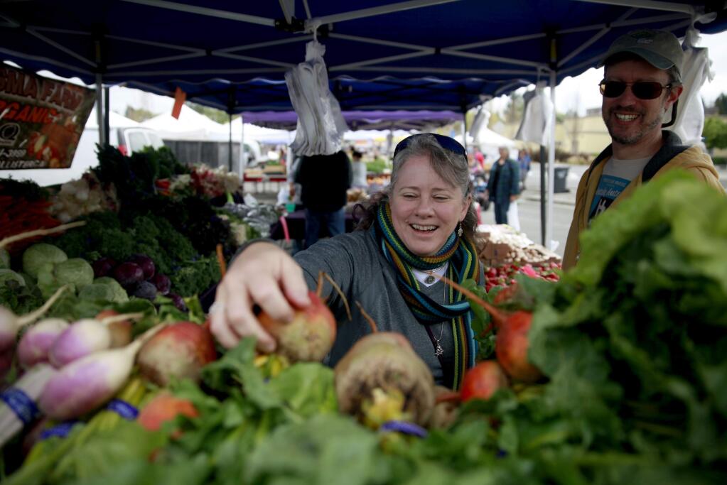 Heidi Sue Roth and her husband David Sandri shop for organic beets and radishes at the Rohnert Park Farmers Market at City Center Drive in Rohnert Park , on Sunday, April 19, 2015. (BETH SCHLANKER/ The Press Democrat)