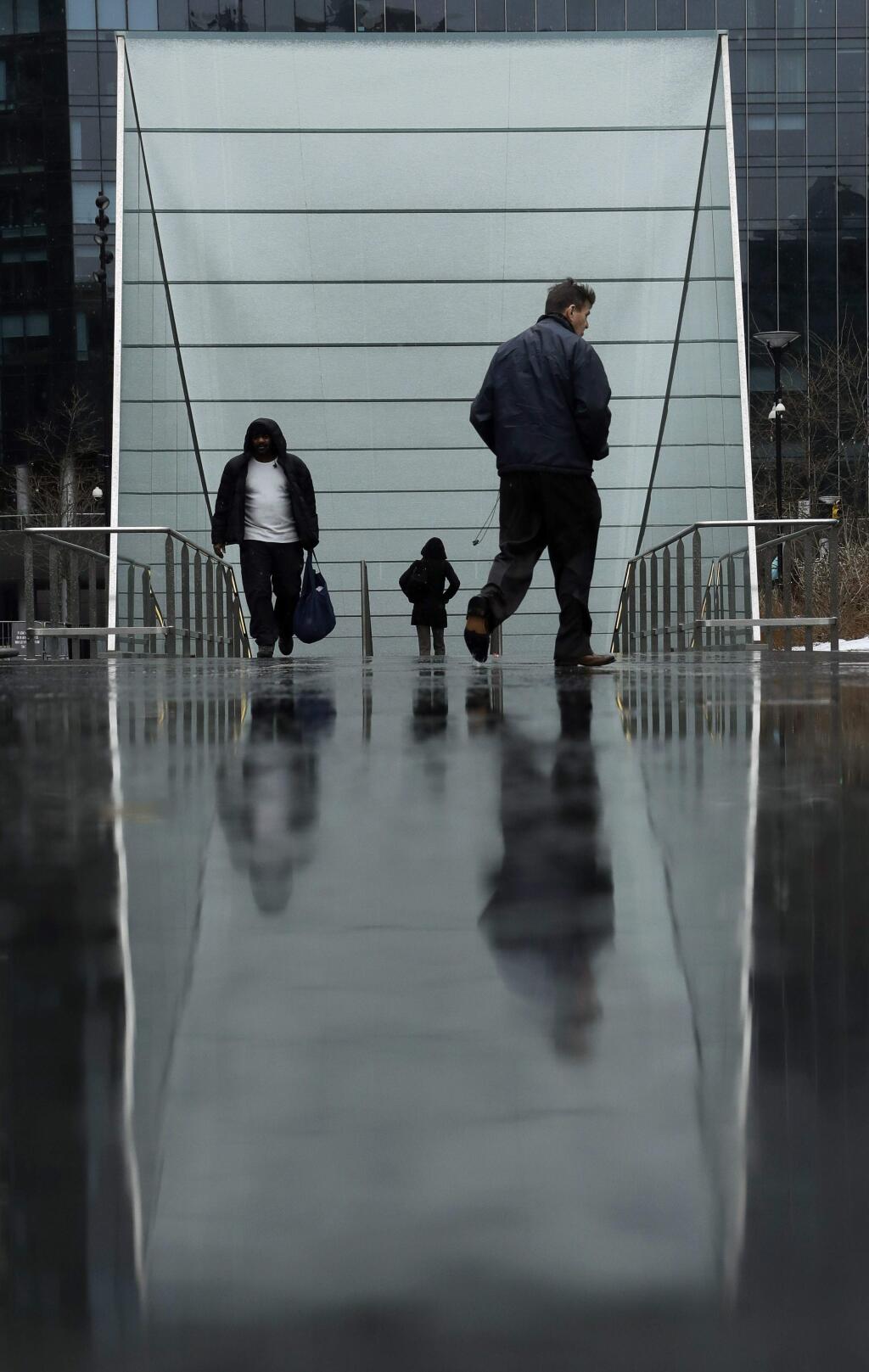 People walk near a subway station entrance at City Hall on Tuesday, March 20, 2018, in Philadelphia. The National Weather Service says a powerful storm packing heavy, wet snow and strong winds could dump up to 18 inches of snow in some locations on Wednesday. (AP Photo/Matt Slocum)