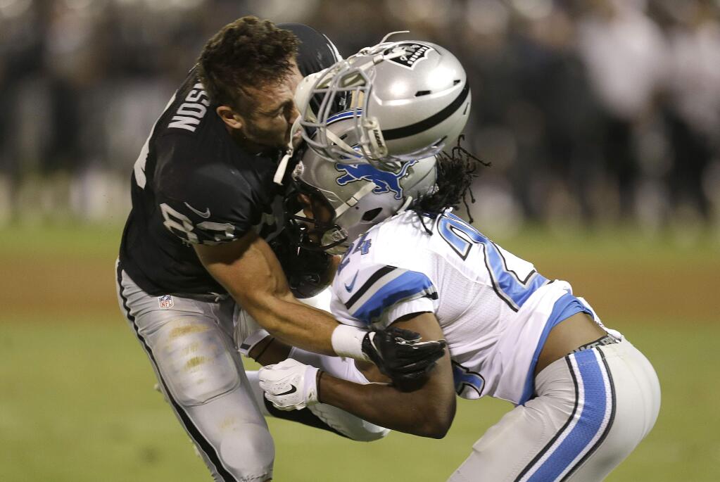Oakland Raiders tight end Scott Simonson, left, loses his helmet and fumbles as he is hit by Detroit Lions defensive back DeJon Gomes during the fourth quarter of a preseason game in Oakland, Calif., Friday, Aug. 15, 2014. Detroit recovered the ball. (AP Photo/Ben Margot)