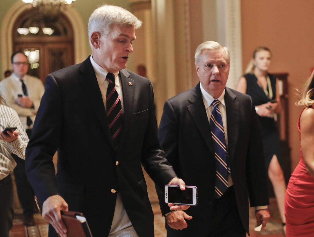 FILE - In this July 13, 2017, file photo, Sen. Bill Cassidy, R-La., left, and Sen. Lindsey Graham, R-S.C., right, talk while walking to a meeting on Capitol Hill in Washington. Senate Republicans are planning a final, uphill push to erase President Barack Obama's health care law. But Democrats and their allies are going all-out to stop the drive. The initial Republican effort crashed in July in the GOP-run Senate. Majority Leader Mitch McConnell said after that defeat that he'd not revisit the issue without the votes to succeed. Graham and Cassidy are leading the new GOP charge and they'd transform much of Obama's law into block grants and let states decide how to spend the money. (AP Photo/Pablo Martinez Monsivais, File)