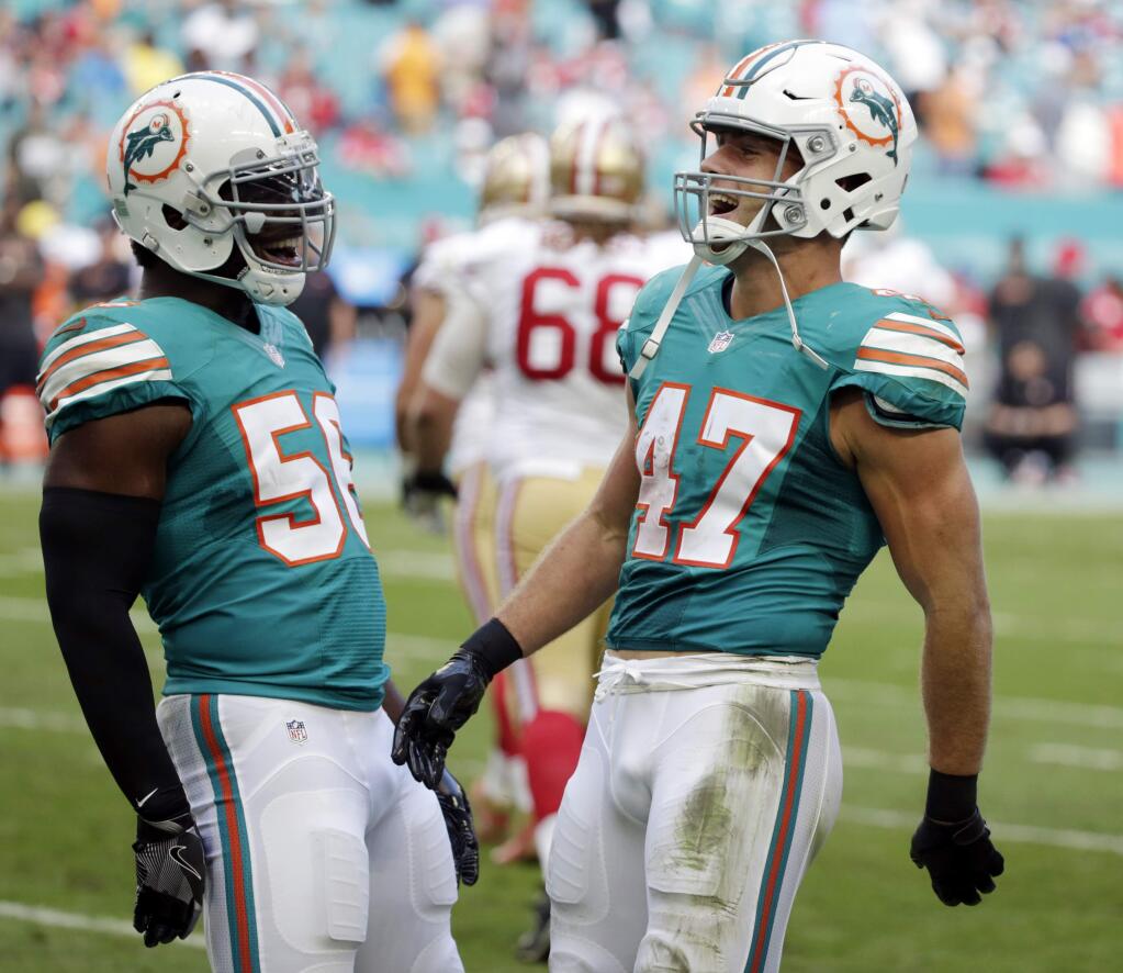 Miami Dolphins middle linebacker Kiko Alonso (47) celebrates an interception with teammate outside linebacker Donald Butler (56), during the second half of an NFL football game against the San Francisco 49ers, Sunday, Nov. 27, 2016, in Miami Gardens, Fla. (AP Photo/Wilfredo Lee)