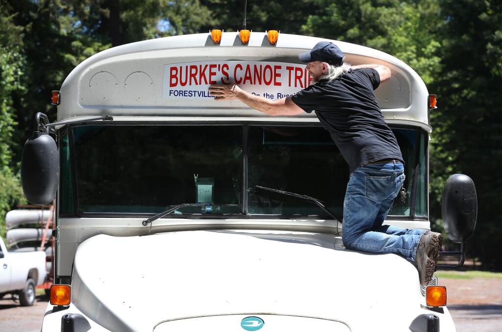 Tony Harley places a magnetic sign onto a bus at Burke's Canoe Trips along the Russian River in Forestville on Thursday, May 21, 2020. The business is awaiting permission to begin operating again under the new health protocols.(Christopher Chung/ The Press Democrat)