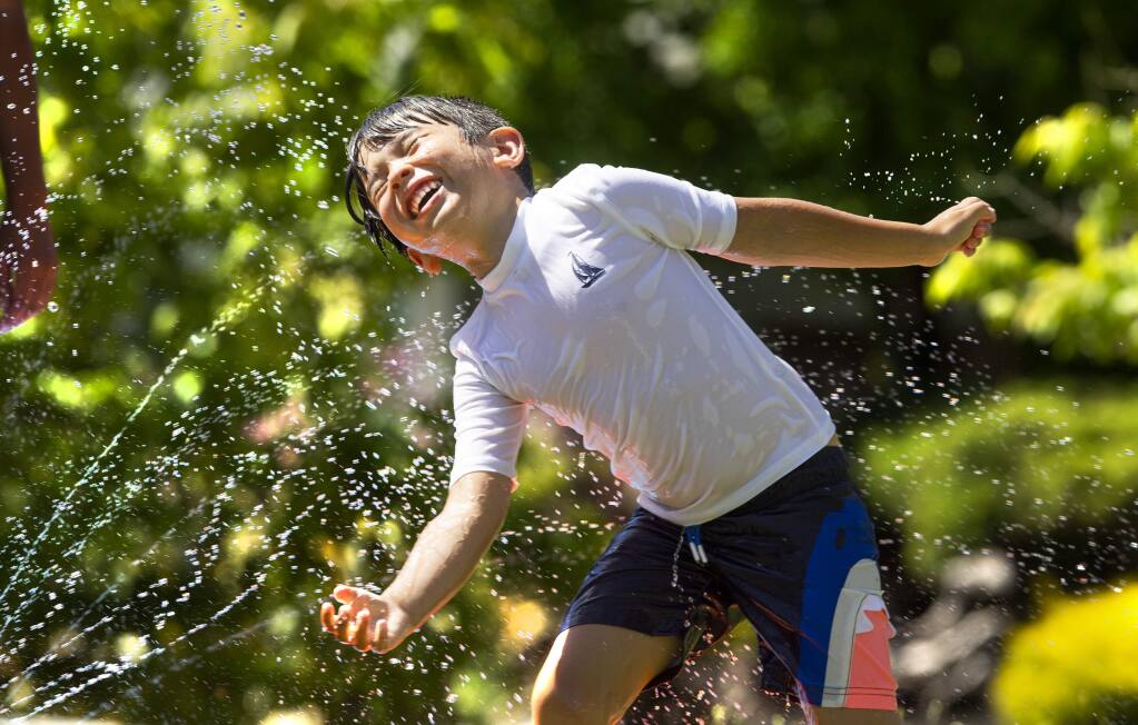 Cohen Parker delights int he spray of his Slip 'N Slide on the grass of his Santa Rosa home on Tuesday, March 26, 2020. (John Burgess/The Press Democrat)