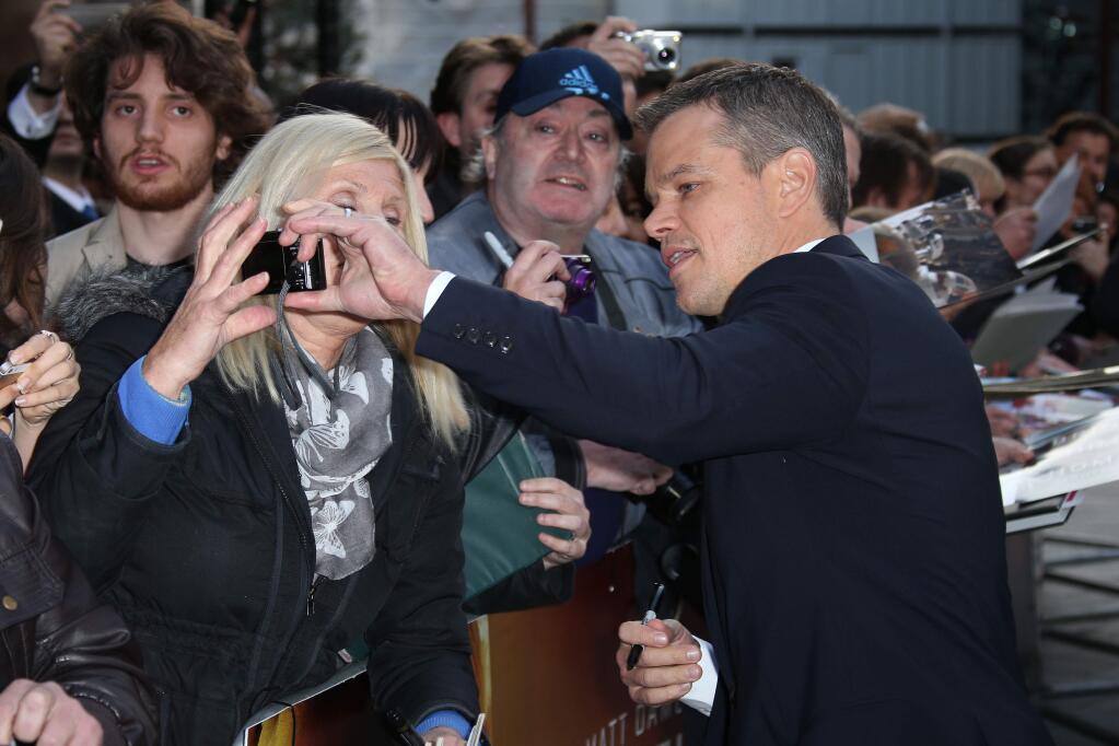 Actor Matt Damon helps a fan out with their camera as he arrives on the red carpet for the European Premiere of The Martian, at a central London cinema, Thursday, Sept. 24, 2015. (Photo by Joel Ryan/Invision/AP)