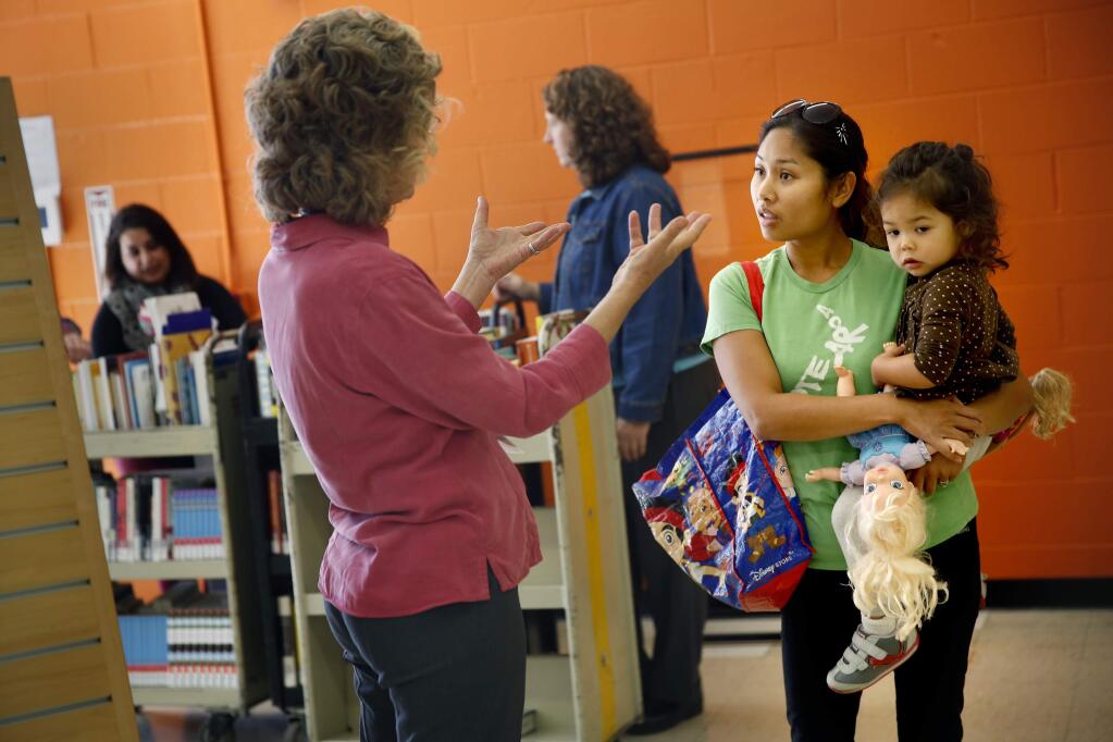 Roseland area residents Jaredel Stevens and her daughter Ruby, 2, talk with librarian Judith Rousseau, center, on the opening day of the Roseland Community Library in Santa Rosa, on Tuesday, November 3, 2015. (BETH SCHLANKER/ The Press Democrat)
