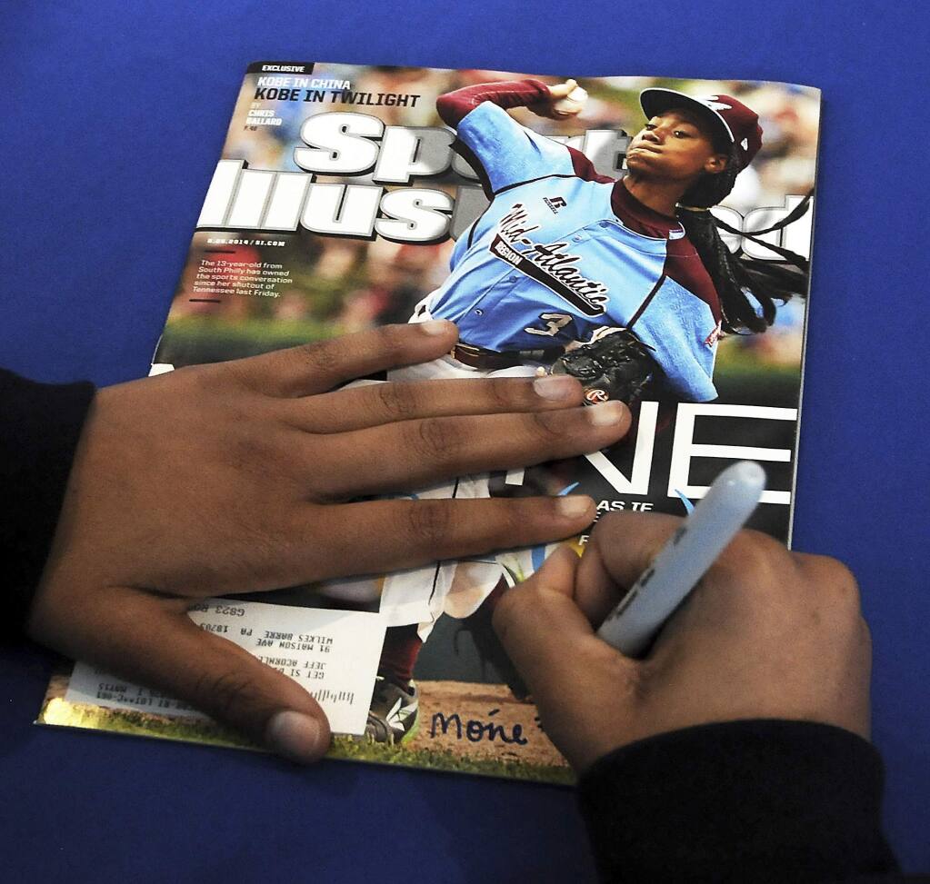 FILE - In this Saturday, Feb. 27, 2016 file photo, Mo'ne Davis, 14, of Philadelphia, signs an autograph for a fan on the cover of Sports Illustrated magazine at PNC Field in Moosic, Pa. Little-known media company Maven, Sports Illustrated's new manager, says the sports magazine is cutting more than 40 jobs out of a staff of 150. Maven spokesman Greg Witter says it will add 200 contractors to cover college and professional sports teams for Sports Illustrated. Maven struck a licensing deal to operate Sports Illustrated with the magazine's new owner, branding company Authentic Brands Group, in June. (Butch Comegys/The Times-Tribune via AP, File)