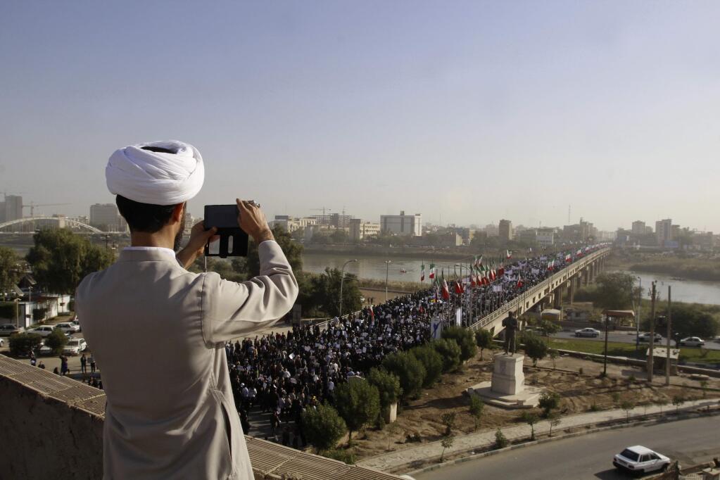 In this photo provided by the Iranian Students' News Agency, a clergyman takes a picture of a pro-government demonstration in the southwestern city of Ahvaz, Iran, Wednesday, Jan. 3, 2018. Tens of thousands of Iranians took part in pro-government demonstrations in several cities across the country on Wednesday, Iranian state media reported, a move apparently seeking to calm nerves after a week of protests and unrest that have killed at least 21 people. (Mohammad Ahangari/ISNA via AP)