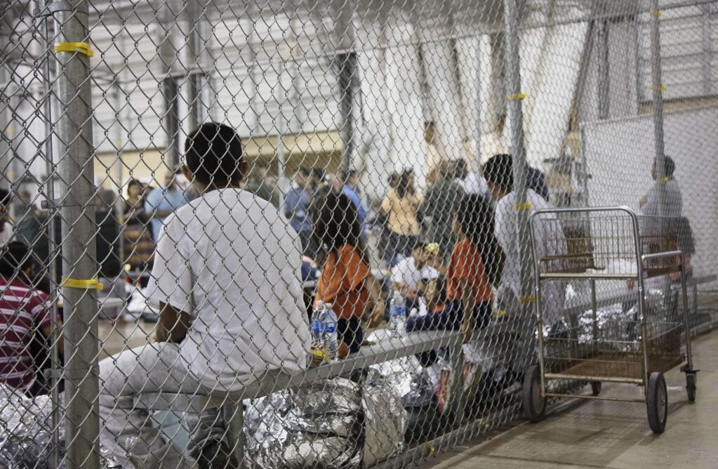 FILE - In this June 17, 2018 file photo provided by U.S. Customs and Border Protection, people who've been taken into custody related to cases of illegal entry into the United States, sit in one of the cages at a facility in McAllen, Texas. (U.S. Customs and Border Protection's Rio Grande Valley Sector via AP)