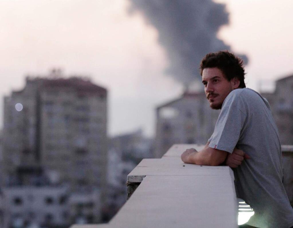 This photo taken in August, 2014 shows Associated Press video journalist Simone Camilli on a balcony overlooking smoke from Israeli Strikes in Gaza City. Camilli, 35, was killed in an ordnance explosion in the Gaza Strip, on Wednesday, Aug. 13, 2014. (AP Photo/Lefteris Pitarakis)