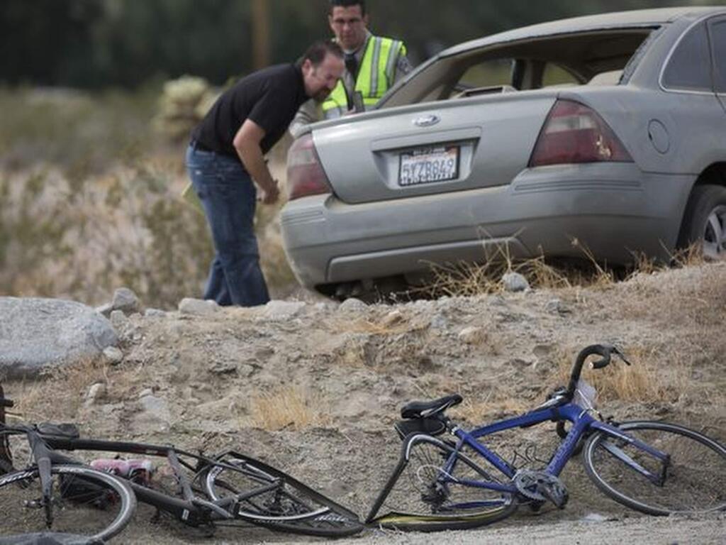 California Highway Patrol investigators inspect a vehicle that struck two cyclists participating in the 2018 Tour de Palm Springs near Indio Hills, Calif., Saturday, Feb. 10, 2018. Police say the car seen was driving down a road at twice the speed limit colliding into cyclists participating in the 100-mile charity bike ride. (Omar Ornelas/The Desert Sun via AP )