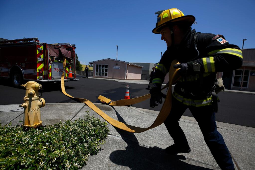 Recruit firefighter Chris Taeuffer, formerly a Rincon Valley volunteer fireghter, pulls a supply hose to connect a fire engine to a hydrant during the Sonoma County Fire District Firefighter Recruit Academy at Santa Rosa Junior College Public Safety Center in Santa Rosa,  Wednesday, May 29, 2019. (Alvin Jornada / The Press Democrat file)