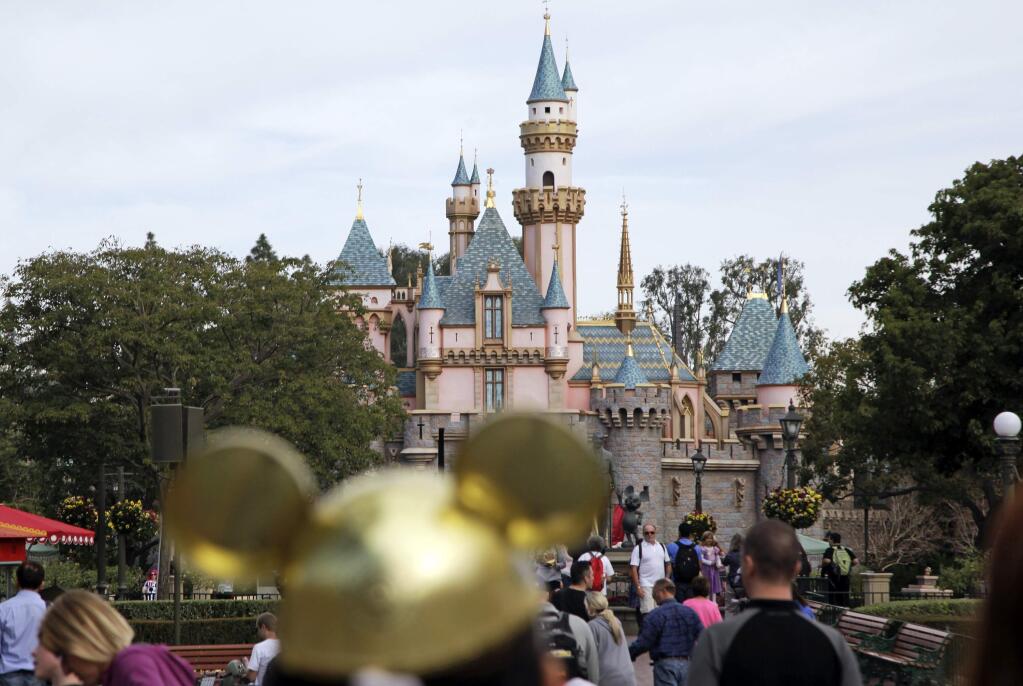 FILE - In this Jan. 22, 2015 file photo, visitors walk toward the Sleeping Beauty's Castle in the background at Disneyland Resprt in Anaheim, Calif. California health officials have declared an end to the large measles outbreak that originated at Disneyland in December. (AP Photo/Jae C. Hong, File)