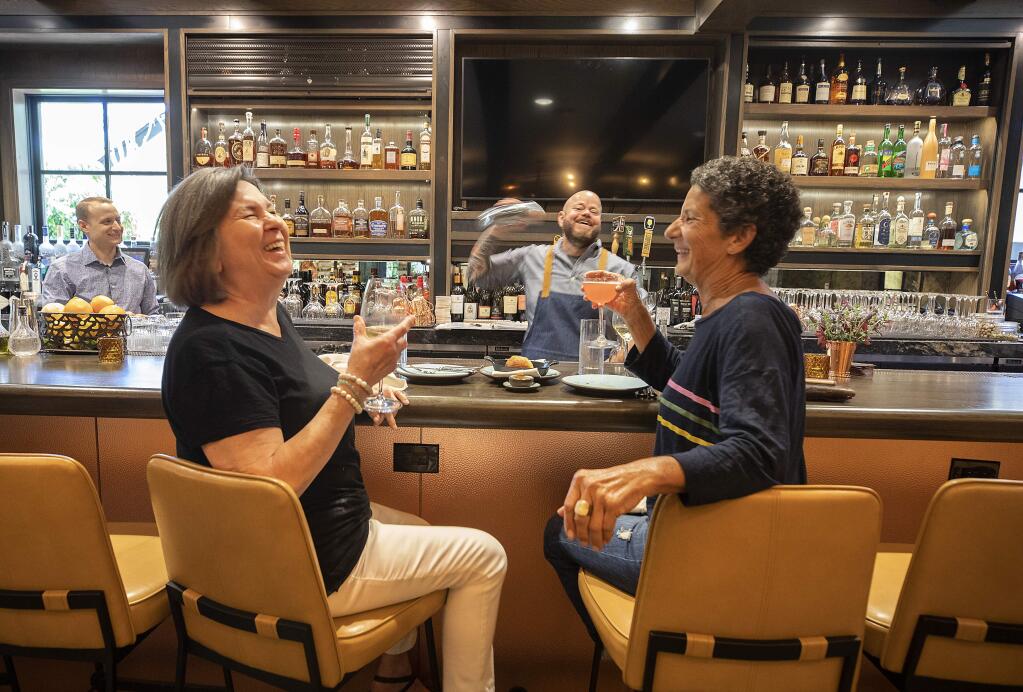 Locals Natalie Pelligrini, left, and Leslie Collins share a laugh and a cocktail made by bartender Robb Gordon of Layla at MacArthur Place restaurant. (John Burgess/The Press Democrat)