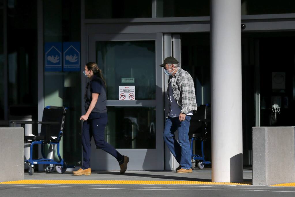 People wearing masks walk out of the ER at Sutter Regional Hospital in Santa Rosa, California on Monday, March 2, 2020. (Beth Schlanker/The Press Democrat)