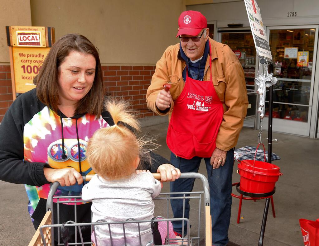 Volunteer Bill Flohr, right, rings his bell for one-year-old Adilyn Heraty and her mother Cherise after they gave a donation to the Salvation Army outside the Yulupa Avenue Safeway in Santa Rosa, California on Friday, November 25, 2016. (Alvin Jornada / The Press Democrat)
