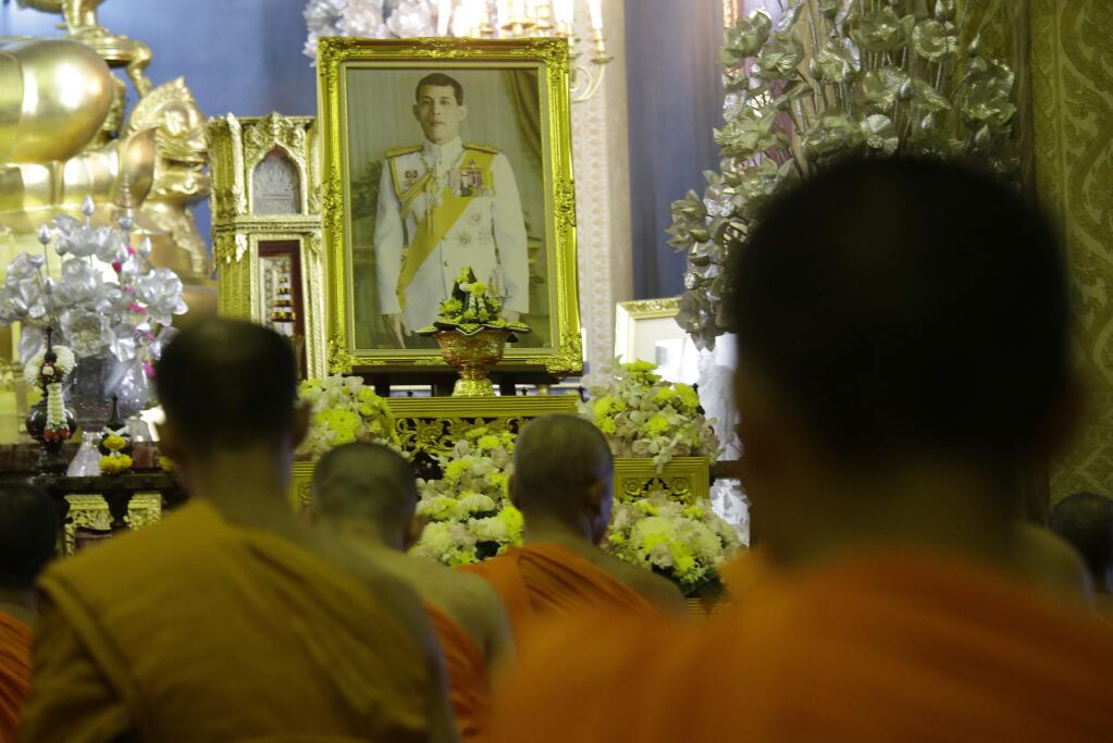 Thai buddhist monks pray in front of portrait Thailand 's new King Maha Vajiralongkorn Bodindradebayavarangkun at the Marble temple in Bangkok, Thailand, Thursday, Dec. 1, 2016. Thailand has a new king, with the country's crown prince formally taking the throne to succeed his much-revered late father, who reigned for 70 years. (AP Photo/Sakchai Lalit)