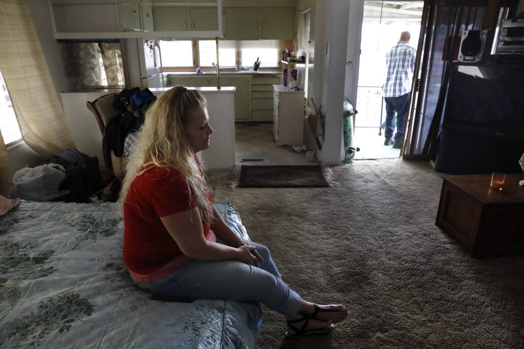 Michelle Trammell sits on her mother's bed inside her home at Journey's End mobile home park in Santa Rosa on Monday, October 1, 2018. (Beth Schlanker/ The Press Democrat)