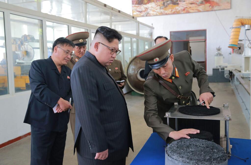 In this undated photo distributed Wednesday, Aug. 23, 2017, by the North Korean government, leader Kim Jong Un, center, visits the Chemical Material Institute of Academy of Defense Science at an undisclosed location in North Korea. North Korea's state media released photos Wednesday that appear to show the designs of one or possibly two new missiles. Concept diagrams of the missiles were seen hanging on a wall behind leader Kim Jong Un while he visited a plant that makes solid-fuel engines for the country's ballistic-missile program.Independent journalists were not given access to cover the event depicted in this photo. (Korean Central News Agency/Korea News Service via AP)