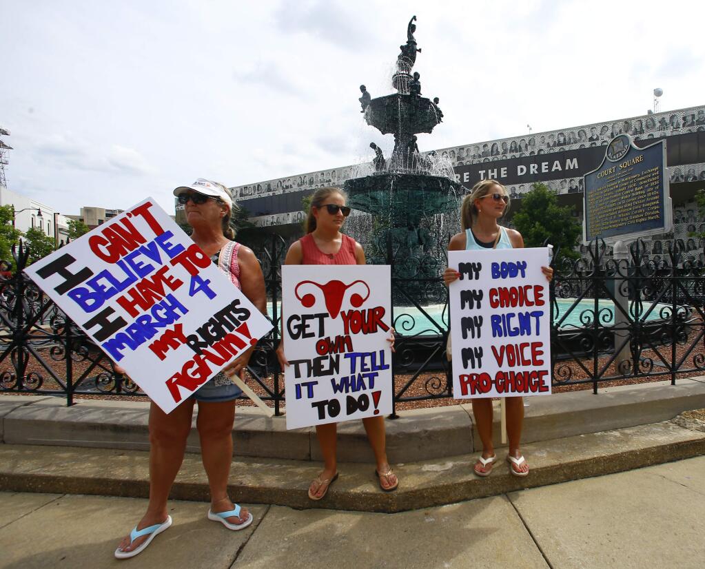 Women hold signs as they gather to march to the Capitol for women's rights, Sunday, May 19, 2019, in Montgomery, Ala. (AP Photo/Butch Dill)