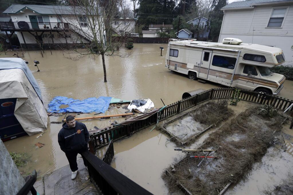 Paul Peterson, bottom left, surveys his flooded property after the San Lorenzo River overflowed Tuesday, Feb. 7, 2017, in Felton, Calif. Flash flood watches are in place for parts of Northern California down through the Central Coast as heavy rains swamp roads and threaten to overtop rivers and creeks. (AP Photo/Marcio Jose Sanchez)