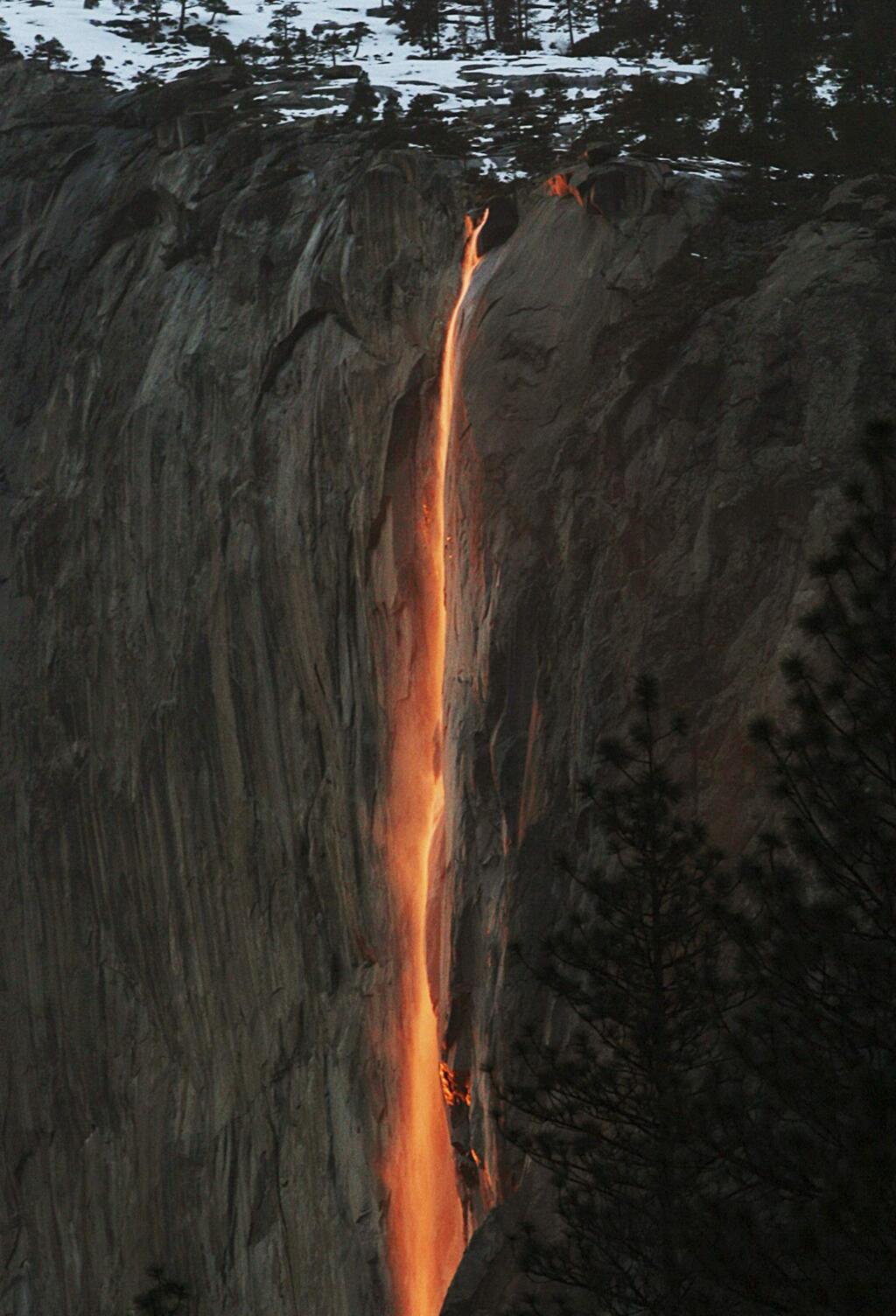 FILE - In this Feb. 16, 2010, file photo, a shaft of sunlight creates a glow near Horsetail Fall, in Yosemite National Park, Calif. Adventurers hoping to see Yosemite National Park's annual 'firefall' will need reservations. At least 50 permits will be issued for each day between Feb. 12 and Feb. 26. The annual event is known to attract over 1,000 sightseers a year. (Eric Paul Zamora/The Fresno Bee via AP, File)