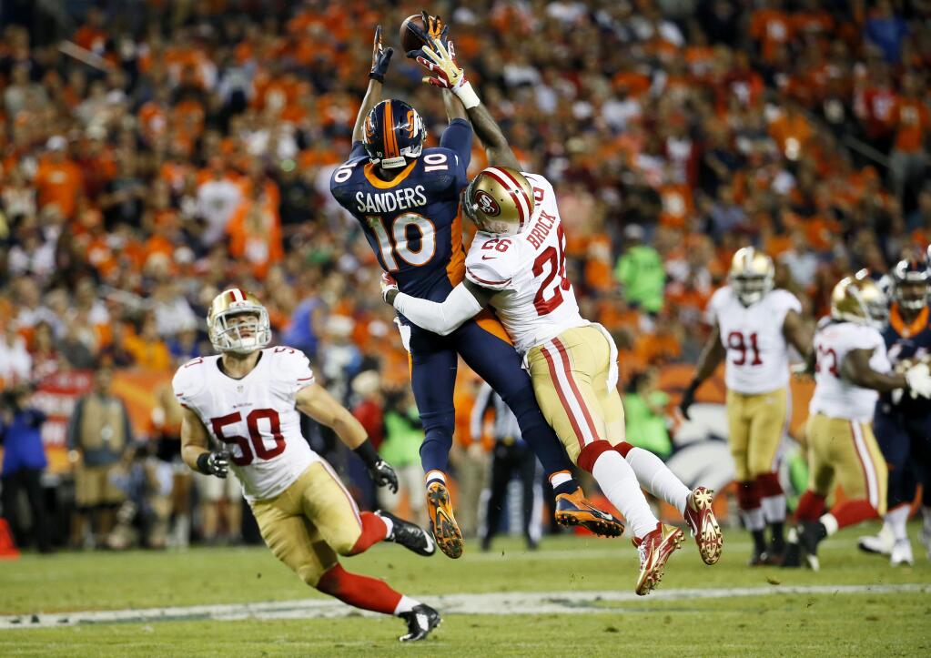 Denver Broncos wide receiver Emmanuel Sanders (10) pulls in a pass as San Francisco 49ers inside linebacker Chris Borland (50) and Tramaine Brock (26) defend during the first half of an NFL football game, Sunday, Oct. 19, 2014, in Denver. (AP Photo/Jack Dempsey)