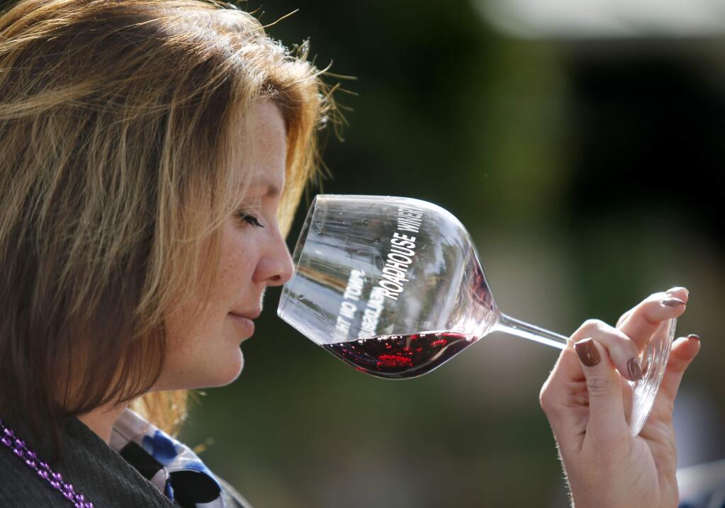 Tara Bell samples a glass of VML Moon Pinot Noir during the Pinot on the River Festival at the Healdsburg Plaza on Sunday, October 23, 2016 in Healdsburg, California . (BETH SCHLANKER / The Press Democrat)