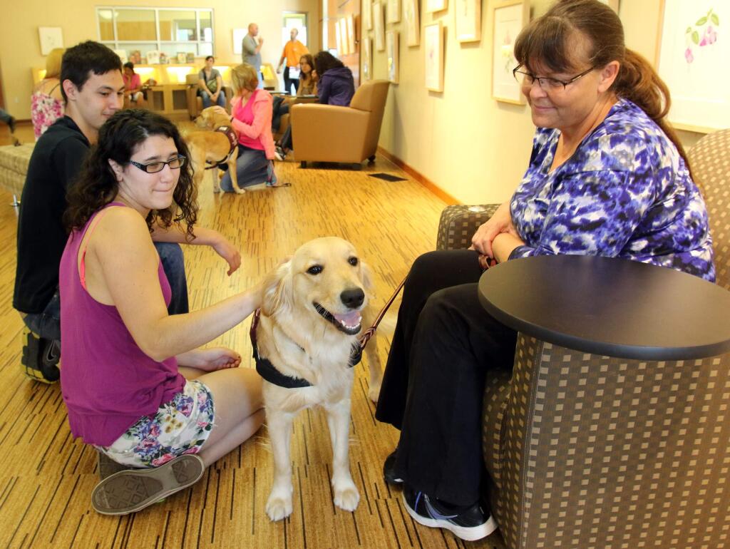Santa Rosa Junior College students Naomi Murphy and Kevin Jacob Daniels, left, enjoy the company of Dosi a golden lab under the watchful eye of trainer Lori Saunders at the SRJC Librairy on the Petaluma campus on Tuesday, April 28, 2015. (SCOTT MANCHESTER/ARGUS-COURIER STAFF)