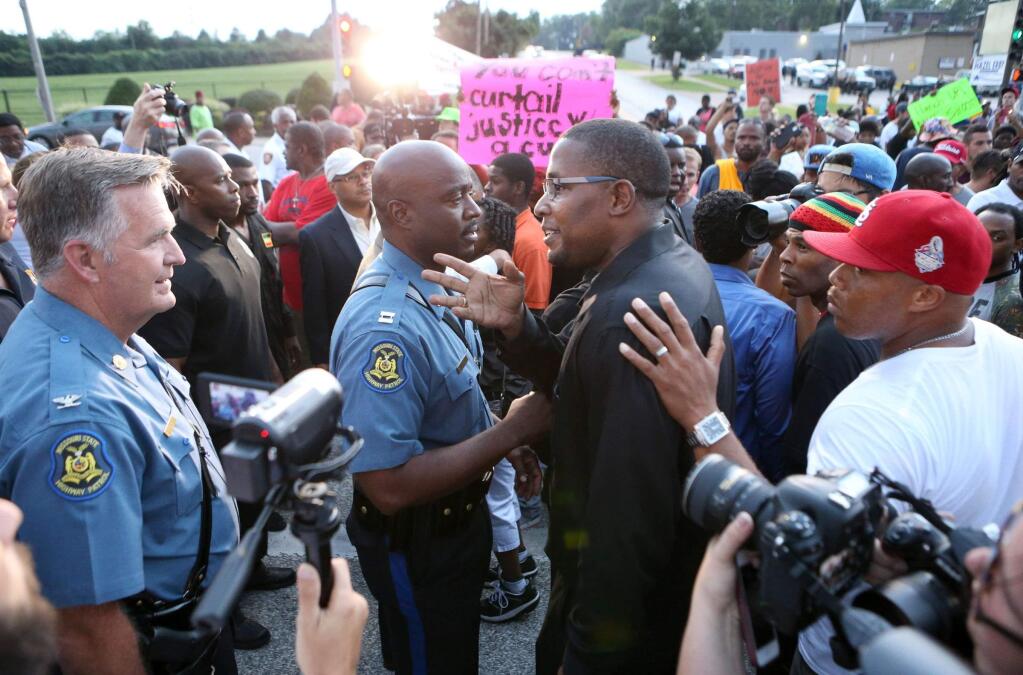 Col. Ron Replogle, left, and Capt. Ron Johnson talk with Malik Shabazz, president of the Black Lawyers for Justice, (center) during a march with protesters along W. Florissant Avenue in Ferguson Missouri on Saturday, Aug. 16, 2014. (AP Photo/St. Louis Post-Dispatch, David Carson)