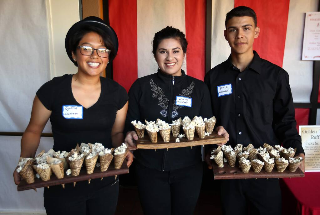 Cynthia Olivares, left, Wendy Ruiz, center and Erick Tinajero all part of Lobo Unity at Elsie Allen, served popcorn to guests who attended the Cirque du SAY fundraiser held at the Friedman Event Center in Santa Rosa, Saturday, April 18, 2015. (Crista Jeremiason / The Press Democrat)