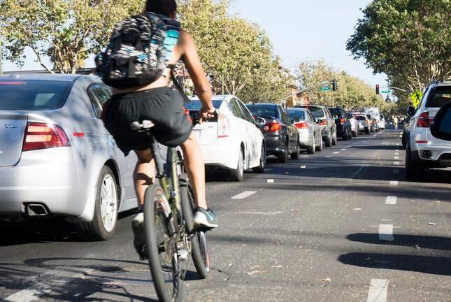 A bicyclist easily bypasses traffic lined up at a red light on Lincoln Avenue, just before Willow Avenue on Sept. 2, 2015. Two pilot programs funded by the MTC's new IDEA Challenge Grant would create an app for cyclists to get more green lights. (Jacqueline Ramseyer/Bay Area News Group)
