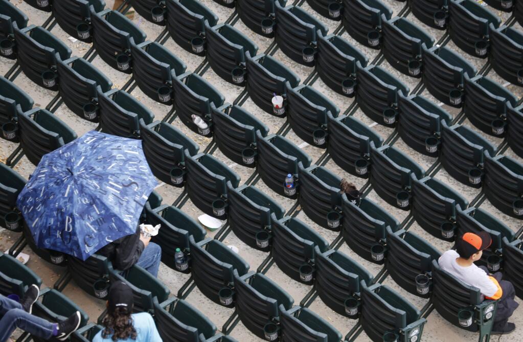 A lone fan seeks cover under an umbrella as a rain delay holds up the start of the first inning of a baseball game betwen the San Francisco Giants and Colorado Rockies Sunday, May 24, 2015, in Denver. (AP Photo/David Zalubowski)