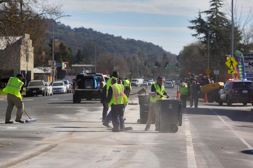 Workers from Recology clean up after garbage truck leaked hydraulic fluid on a stretch of Petaluma Hill Road, near Barham Road, in Santa Rosa on Wednesday, Feb. 14, 2018. (CHRISTOPHER CHUNG/ PD)