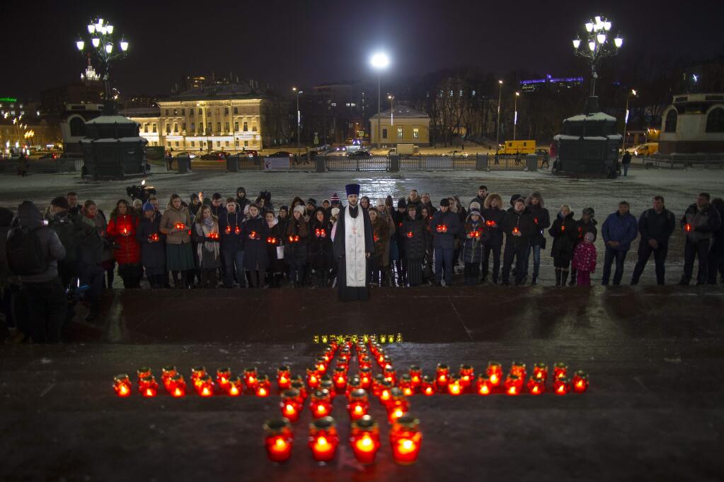 Orthodox youth with a priest gather at the Cathedral of Christ the Savior in Moscow lighting 71 candles in memory of those killed in the An-148 plane crash, Monday, Feb. 12, 2018. A Russian passenger plane carrying 71 people crashed Sunday near Moscow, killing everyone aboard shortly after the jet took off from one of the city's airports. The Saratov Airlines regional jet disappeared from radar screens a few minutes after departing from Domodedovo Airport en route to Orsk, a city some 1,500 kilometers (1,000 miles) southeast of Moscow. (AP Photo/Alexander Zemlianichenko)
