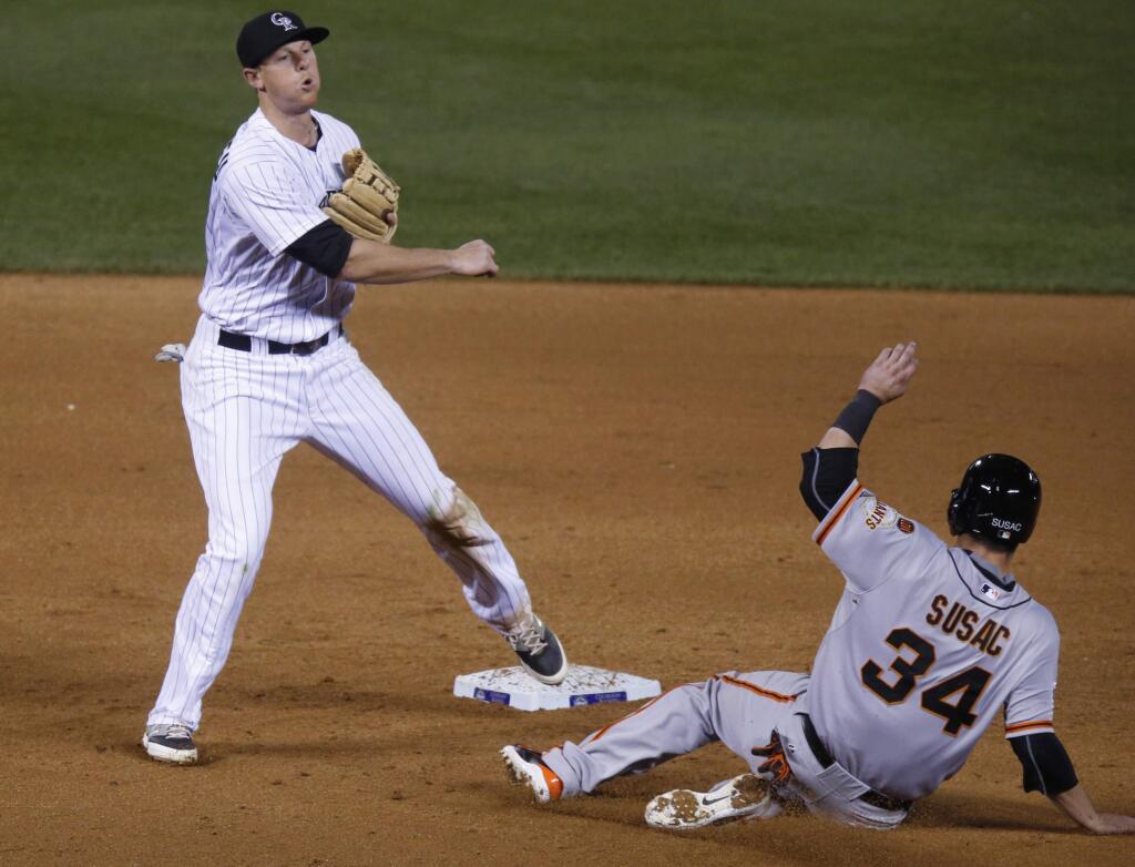 Colorado Rockies second baseman DJ LeMahieu, left, throws to first base after forcing out San Francisco Giants catcher Andrew Susac at second base on the front end of a double play hit into by Casey McGehee in the 10th inning of a baseball game Saturday, April 25, 2015, in Denver. The Giants won 5-4 in 11 innings. (AP Photo/David Zalubowski)