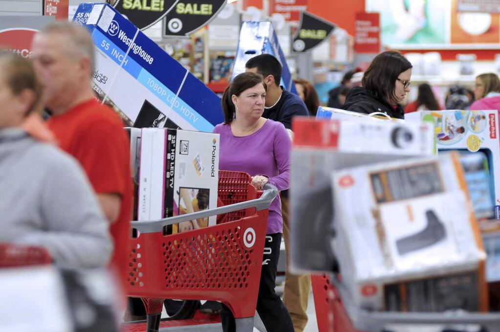 A woman maneuvers her way through Black Friday shoppers at the Target store in Plainville, Mass., shortly after the store opened at 1 a.m. Friday, Nov. 25, 2016. Large screen televisions were among the popular items purchased. Stores open their doors Friday for what is still one of the busiest days of the year, even as the start of the holiday season edges ever earlier. (Mark Stockwell/The Sun Chronicle via AP)