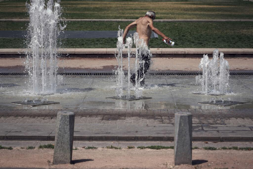 A man cools off in a fountain, in Lyon, central France, Wednesday, July 24, 2019. Europeans are jumping into public fountains and the sea to keep cool as parts of Europe could see a record-breaking heat wave. (AP Photo/Laurent Cipriani)