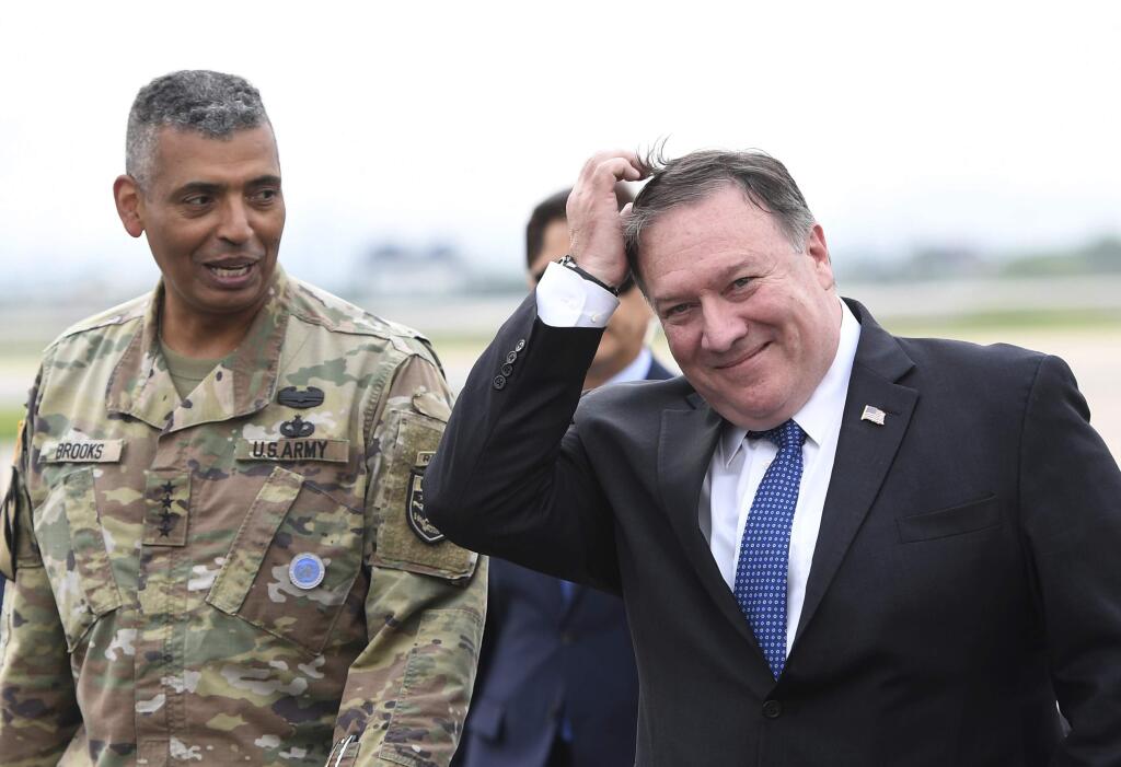 U.S. Secretary of State Mike Pompeo, right, walks with U.S. General Vincent K. Brooks, left, commander of United States Forces Korea, upon his arrival at Osan Air Base in Pyeongtaek Wednesday, June 13, 2018. South Korea's presidential office said Pompeo will meet President Moon Jae-in Thursday morning to discuss the meeting, which made history as the first between sitting leaders of the U.S. and North Korea. (Jung Yeon-je/Pool Photo via AP)