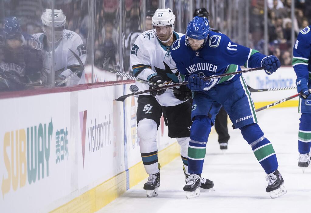 Vancouver Canucks' Josh Leivo, right, checks San Jose Sharks' Joonas Donskoi, of Finland, during the first period of an NHL hockey game in Vancouver, British Columbia, on Monday, Feb. 11, 2019. (Darryl Dyck/The Canadian Press via AP)