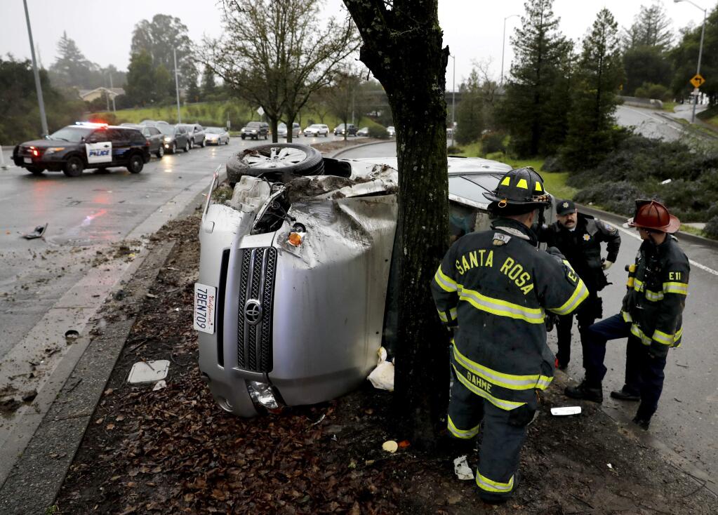 Santa Rosa fire fighters and police officers respond to an accident involving a minivan that flipped and crashed into a tree on Fountaingrove Parkway near Altruria Drive in Santa Rosa, Sunday, Feb. 19, 2017. (BETH SCHLANKER/ The Press Democrat)