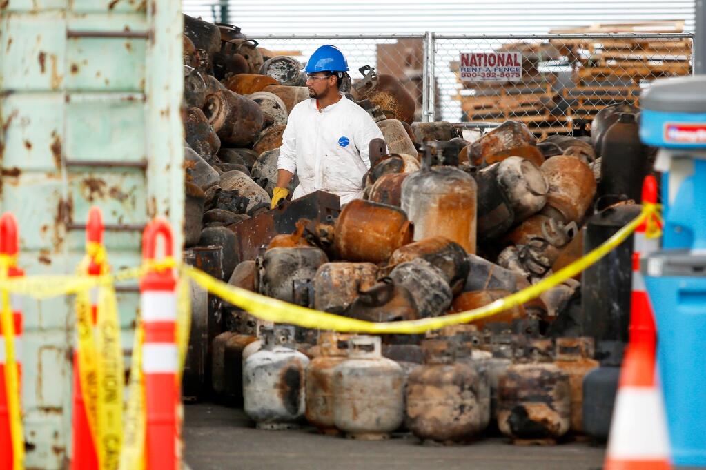 A worker walks between piles of propane tanks that were destroyed during the recent wildfires, at the EPA's Sonoma County staging area for household hazardous waste in Windsor, California on Thursday, November 2, 2017. (Alvin Jornada / The Press Democrat)