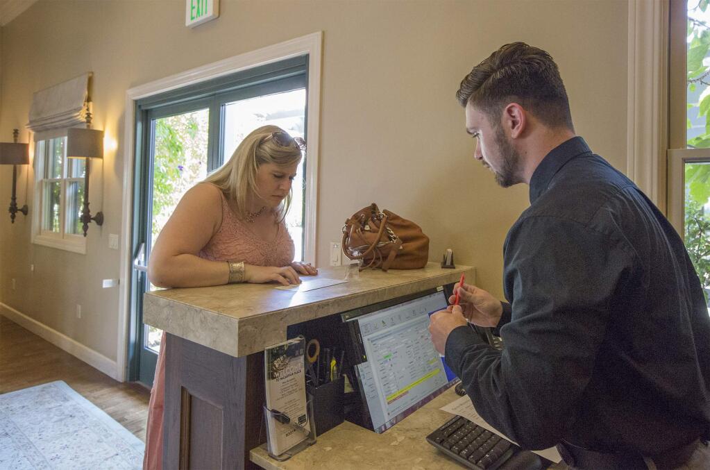 Front desk agent Mark Watson helps Maria Altieri check in for a few days of R&R at MacArthur Place on Wednesday, Aug 23. (Photo by Robbi Pengelly/Index-Tribune)