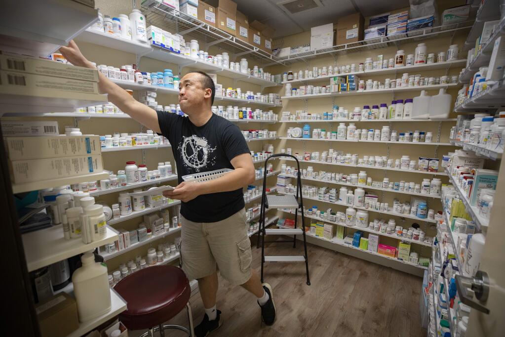 Sebastopol Family Pharmacy technician Edward Kang gathers drugs to fill an order at the small independent business. (photo by John Burgess/The Press Democrat)
