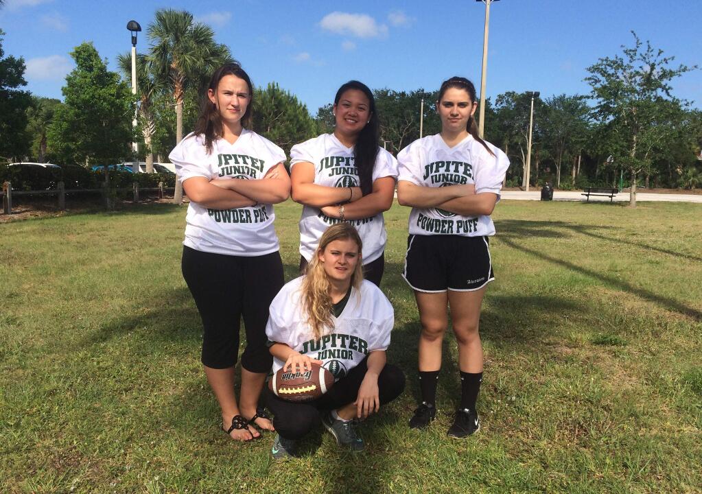 Jupiter High powder-puff football players Caitlin Walsh, Megan Mendoza, Haley Osborne and Savannah Tardonia (in front with ball) pose for a group photo, Monday, May 2, 2016, in Jupiter, Fla. The clock has run out on what boosters describe as the nation's last tackle powderpuff football game. For 50 years at Jupiter High School, school spirits have been stoked by the annual football game pitting senior girls against juniors in a true test of toughness. But safety concerns prompted the principal to cancel this year's game, and many people in the middle-class suburb on the Palm Beach coast feel blindslided. (AP Photo/Terry Spencer)