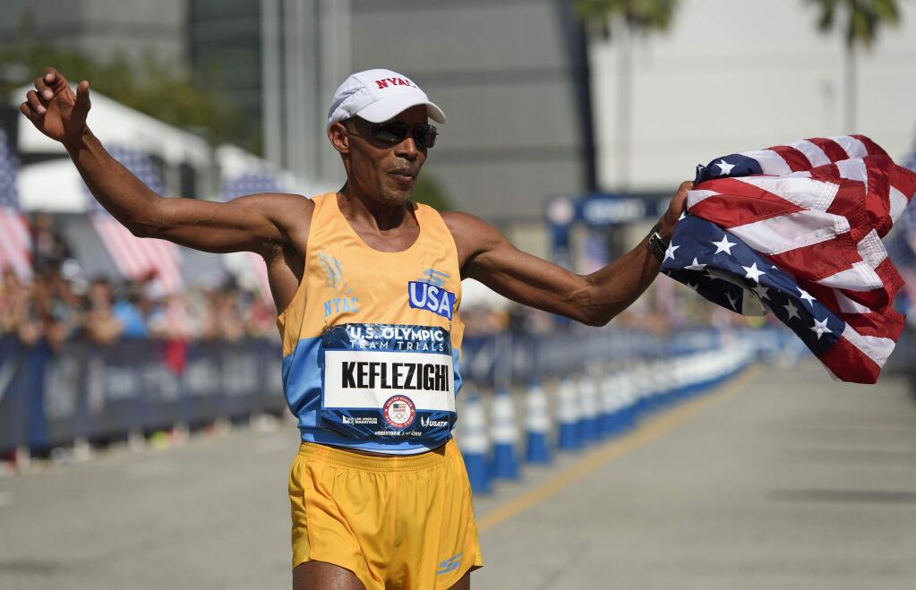 Meb Keflezighi waves the United States flag after he finishes during the 2016 U.S. Olympic marathon trials in Los Angeles on Feb. 13. (Kelvin Kuo / Associated Press)