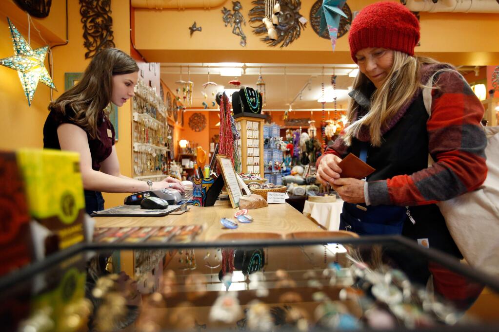 Gina Cloud, right, of Bloomfield purchases some last-minute Christmas presents from sales associate Emily Scott at Kindred Fair Trade Handcrafts in downtown Santa Rosa, California on Friday, December 22, 2017. (Alvin Jornada / The Press Democrat)