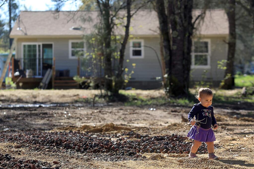 15 month-old Emilia Lord navigates her new back yard, Friday March 18, in Middletown. The family, including the toddler, Justin Lord and Courtney Van Leuven lost their home to the Valley fire in September 2015 and are moving in to a new home (background) built by Hope City. (Kent Porter / Press Democrat) 2016